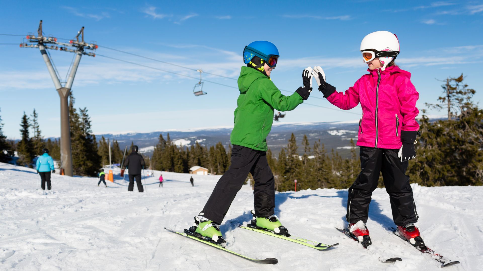 Kinderen skiën en geven elkaar een high-five op een besneeuwde berghelling.