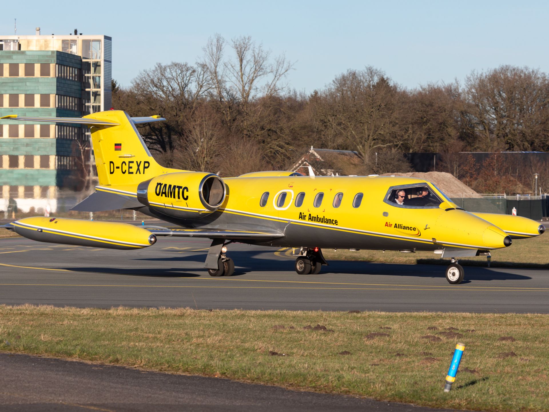 Een gele ambulancevliegtuig op de startbaan bij een luchthaven.